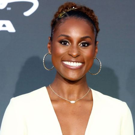 Issa Rae in a white coat poses for a picture.